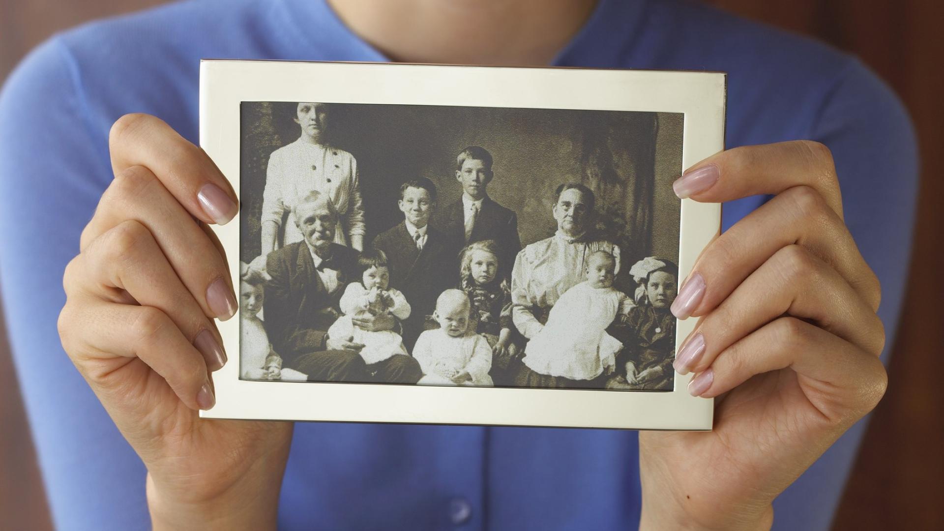 Hands holding out an old multigenerational family photo