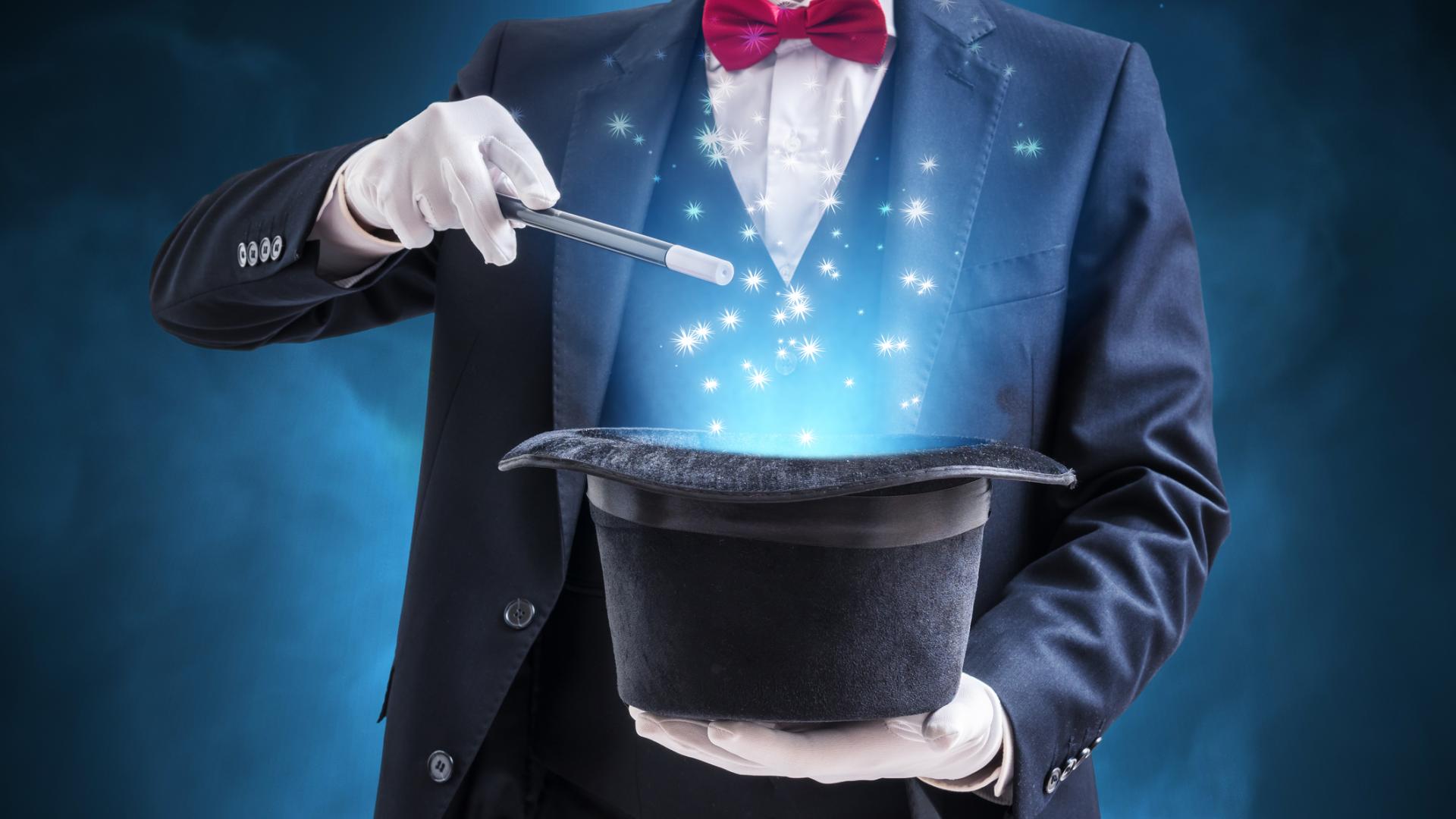 Magician holding a top hat and waving a magic wand over the hat with blue sparkles coming out of the hat