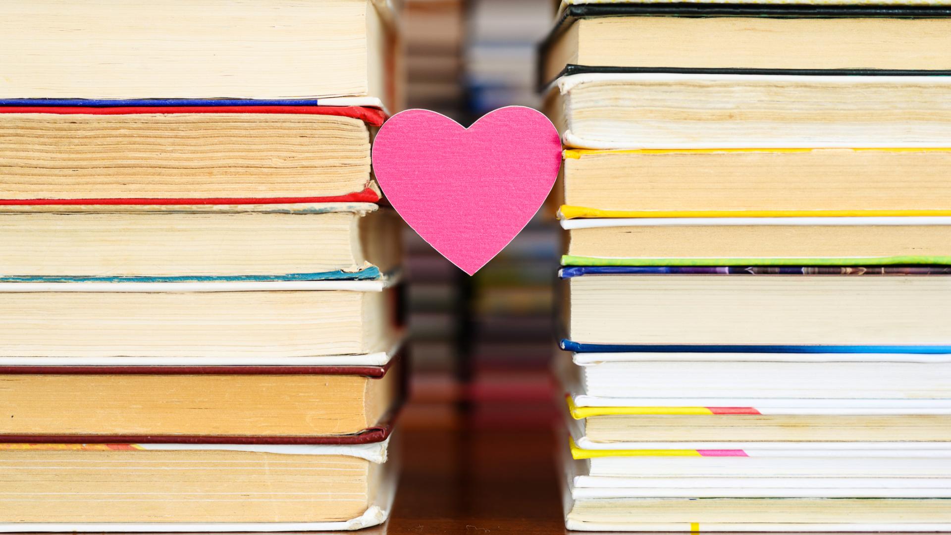 Pink paper heart sandwiched between two stacks of books