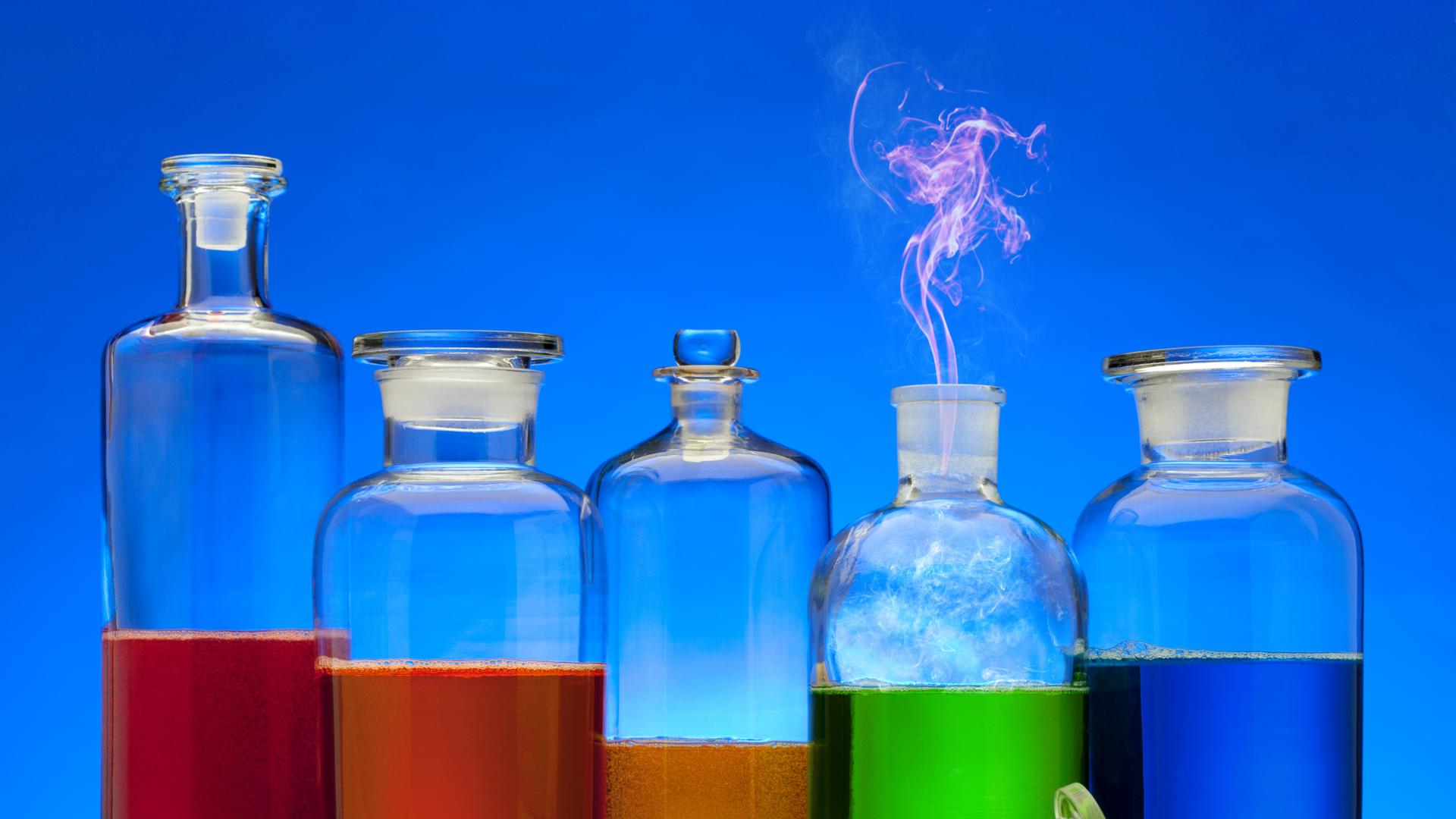 Five glass containers in a row with different coloured liquid to mimic a rainbow