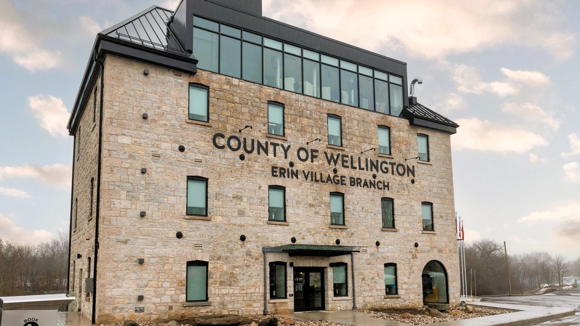A large four story stone building with the words County of Wellington on the face