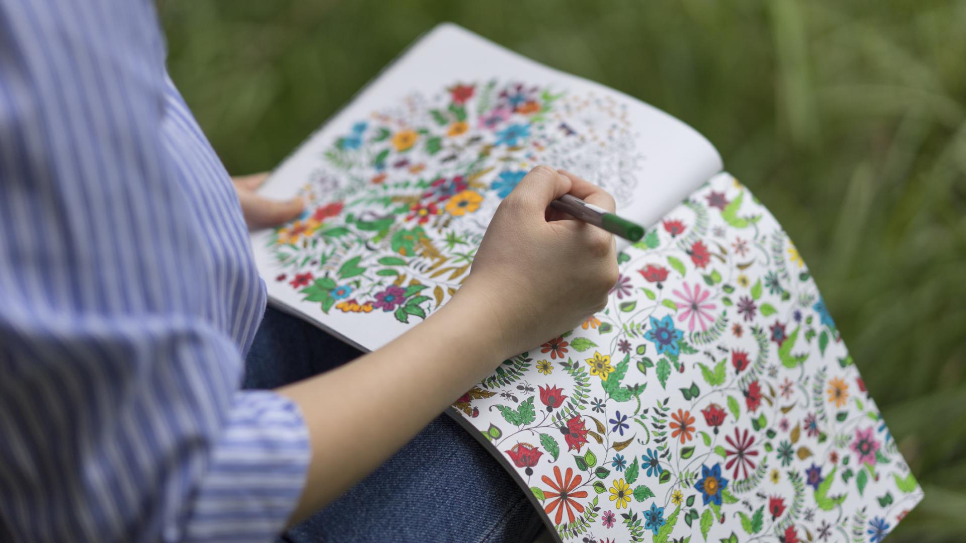A photo of a woman colouring in a picture of flowers