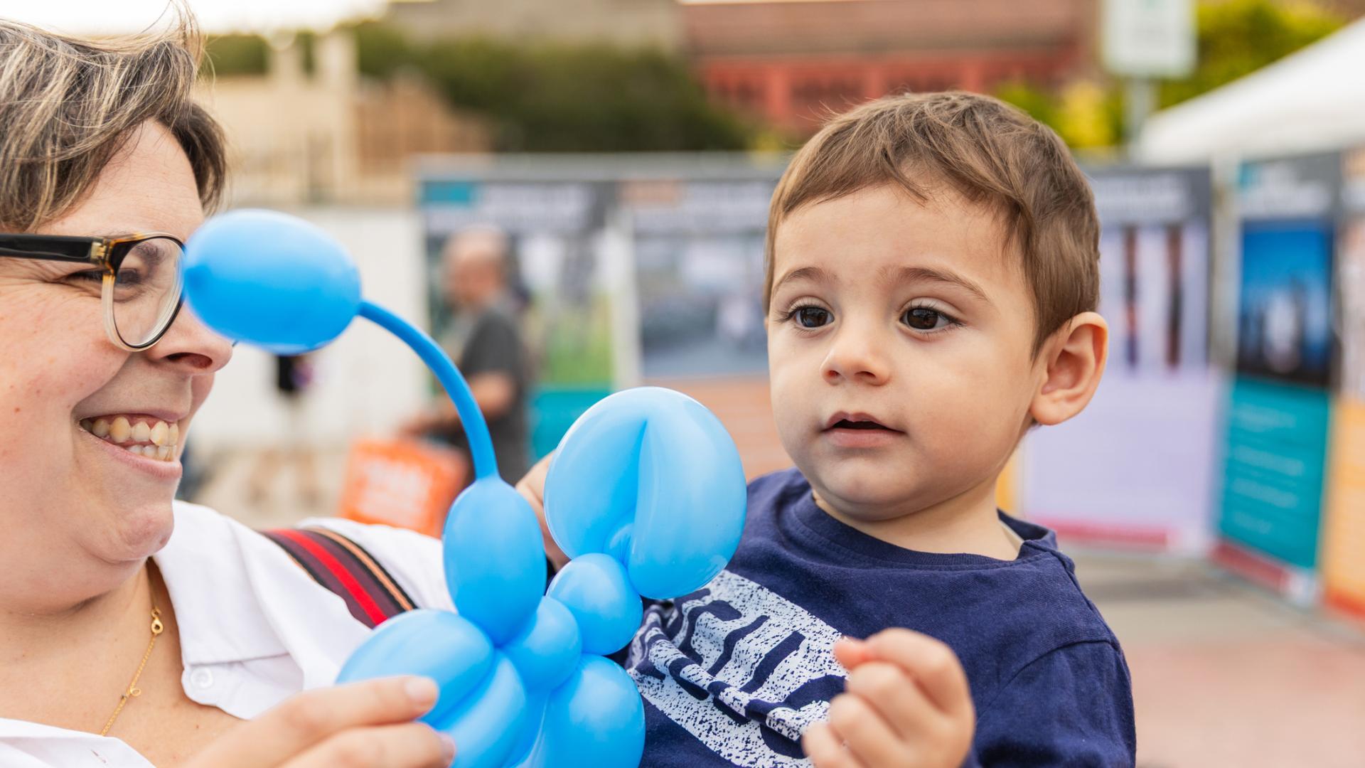 A grandma holds her grandson and shows him a balloon animal
