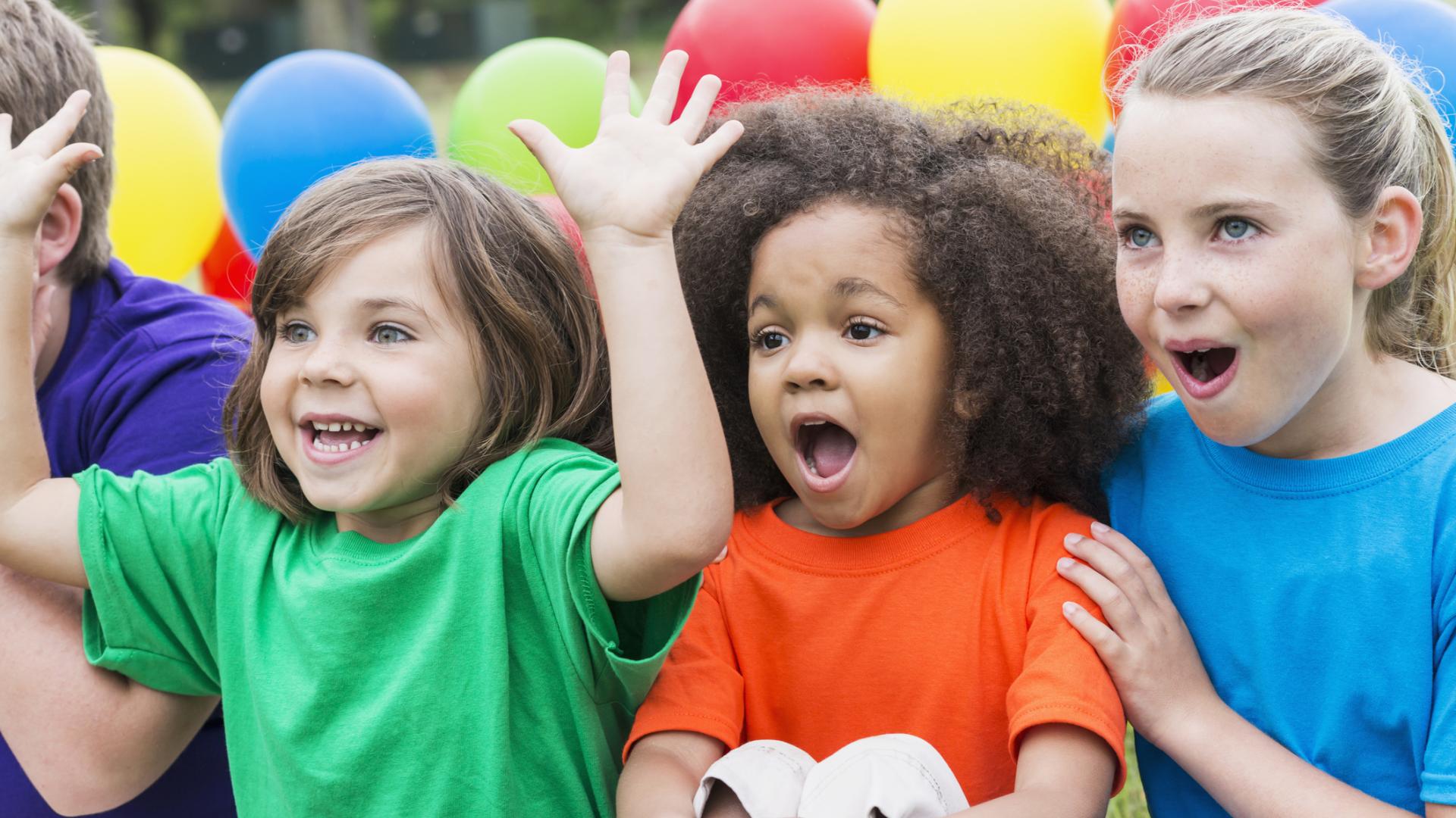 Photo of a group of excited kids with balloons behind them