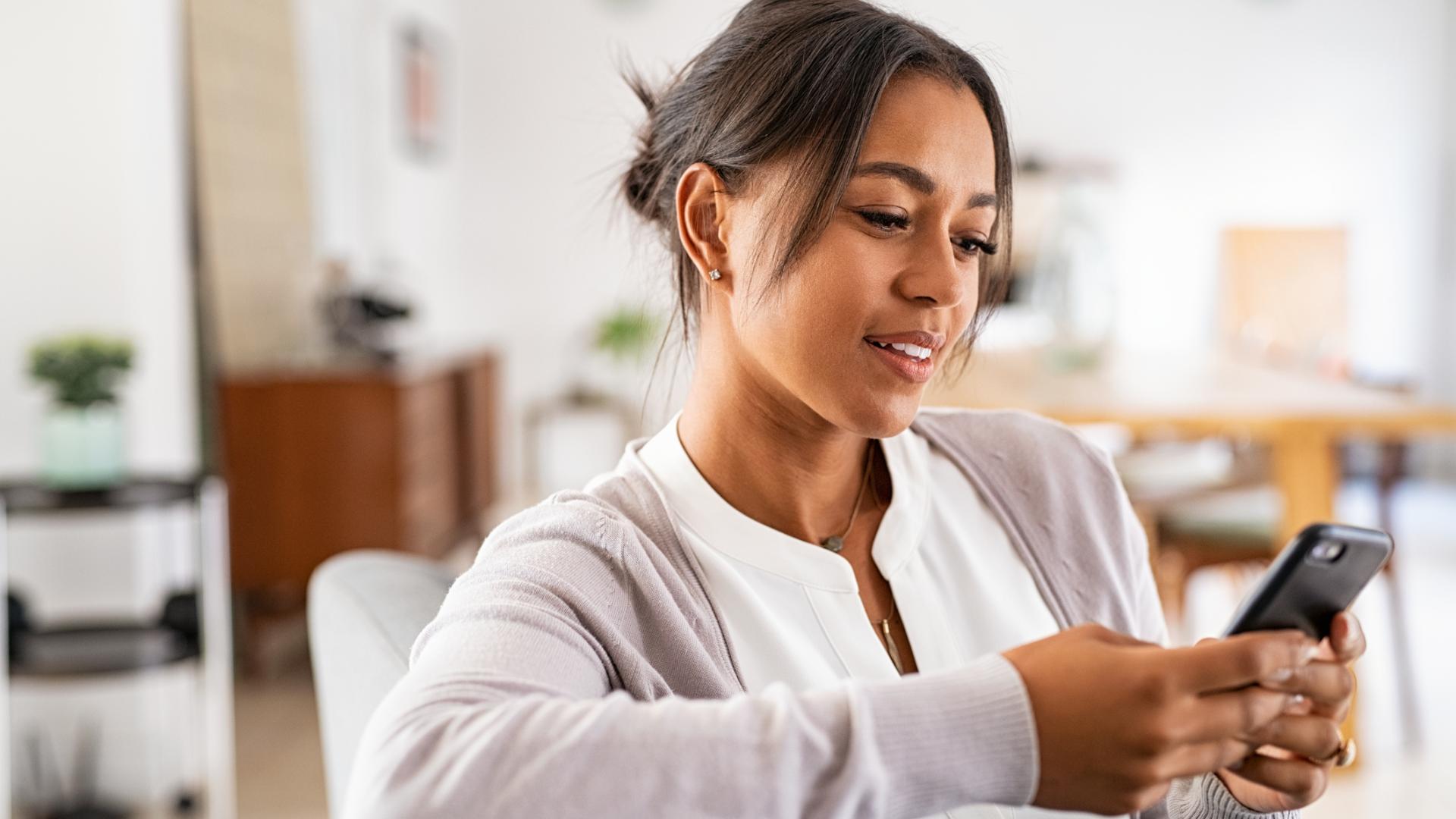 A photo of a woman sitting in a comfortable chair looking at her phone