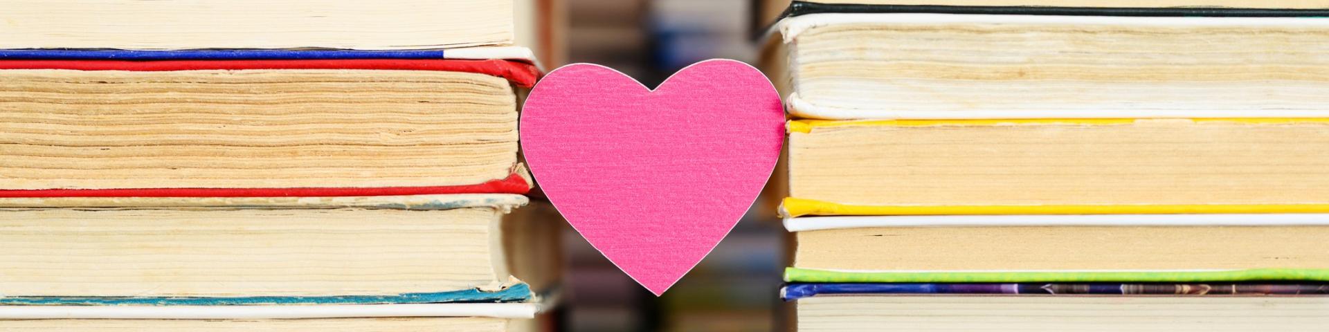 Photo of a pink heart sandwiched between two stacks of books