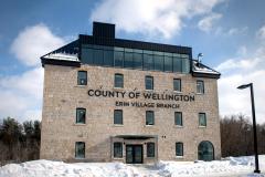 Exterior of a four-story stone building with the words County of Wellington Erin Village Branch installed at the top