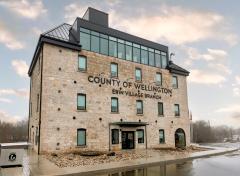 A large four story stone building with the words County of Wellington on the face