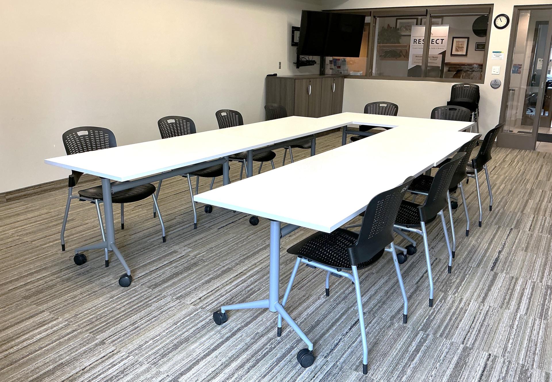 A photo of the Puslinch library meeting room with a table and chairs and wall mounted tv
